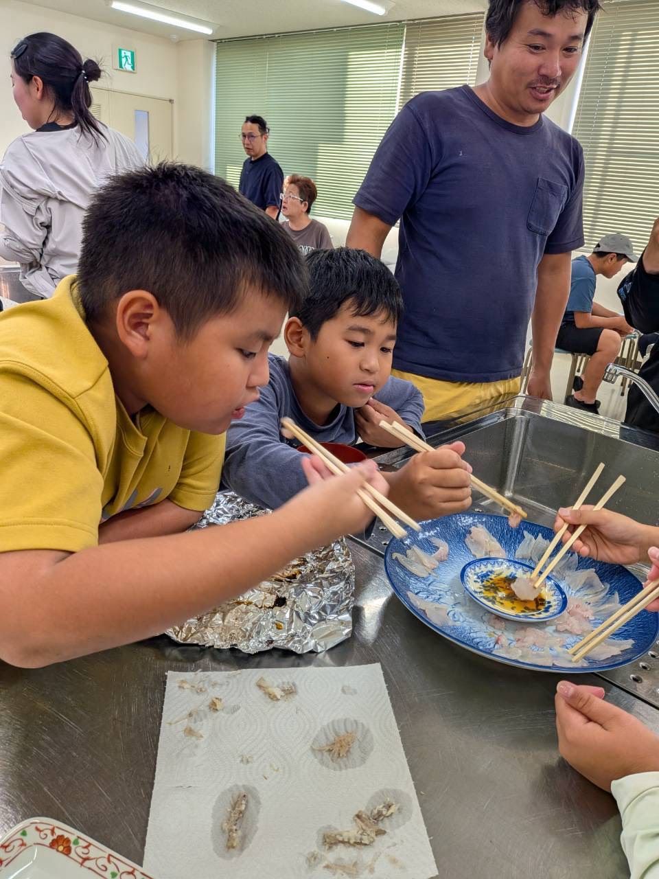 魚の刺身を食べる子どもたち